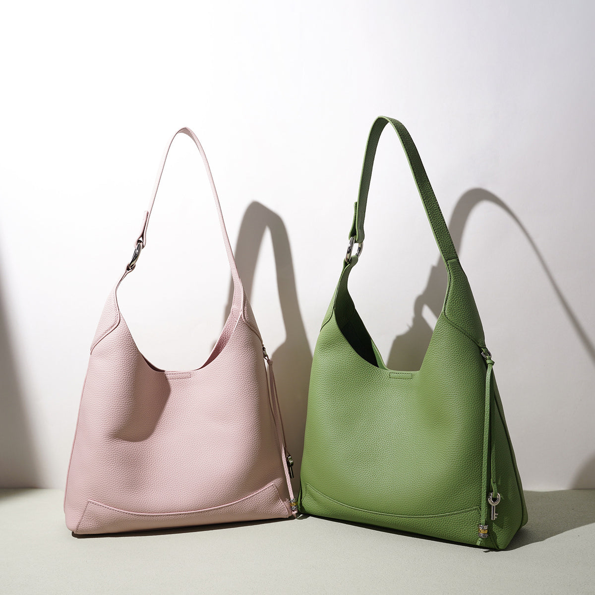 Pink and green leather shoulder bags side by side