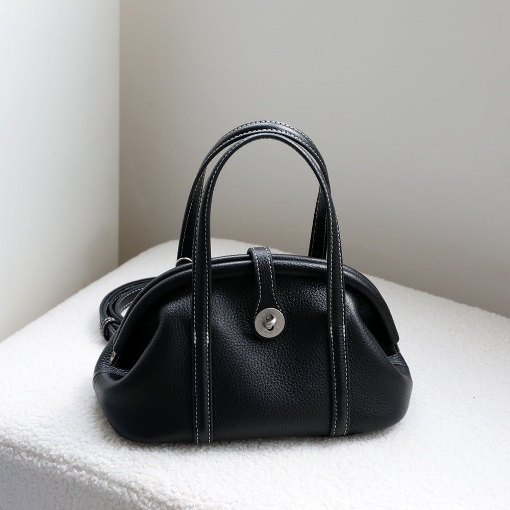 Black leather top-handle bag on a white surface